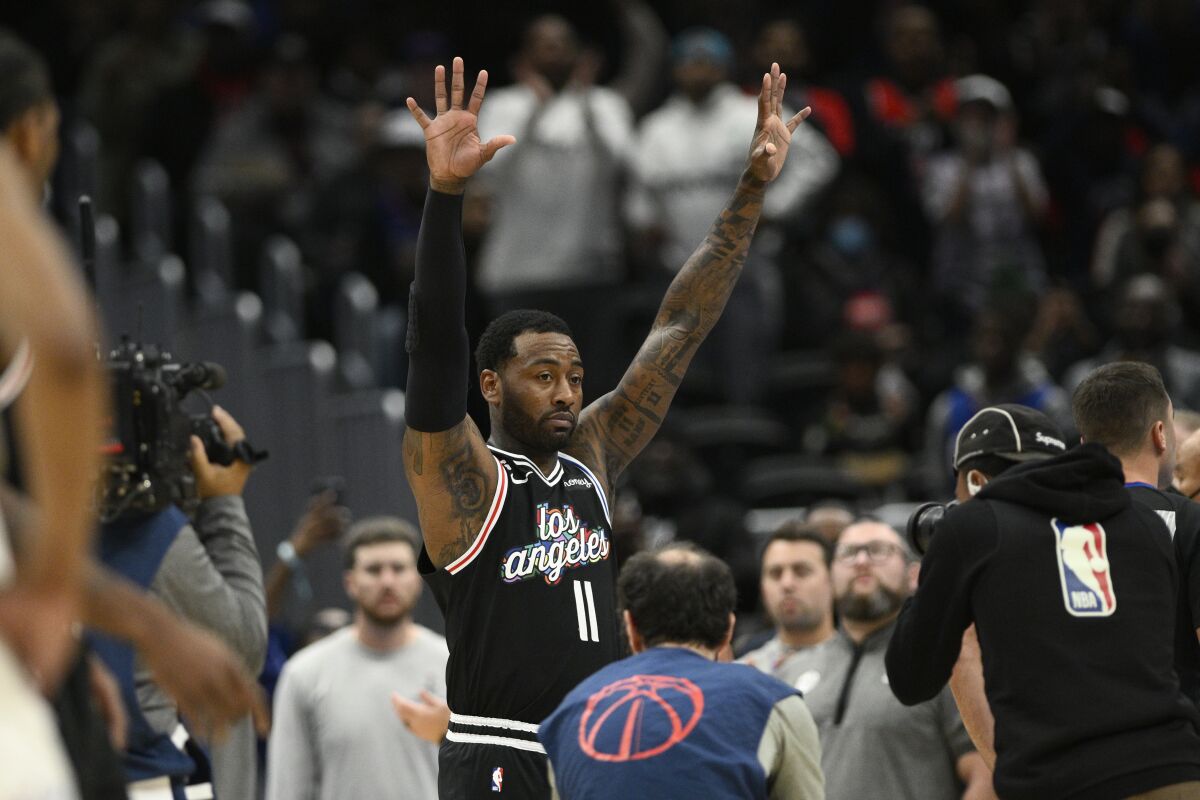 Clippers guard John Wall raises his hands to acknowledge the crowd as a tribute video plays on a videoboard.